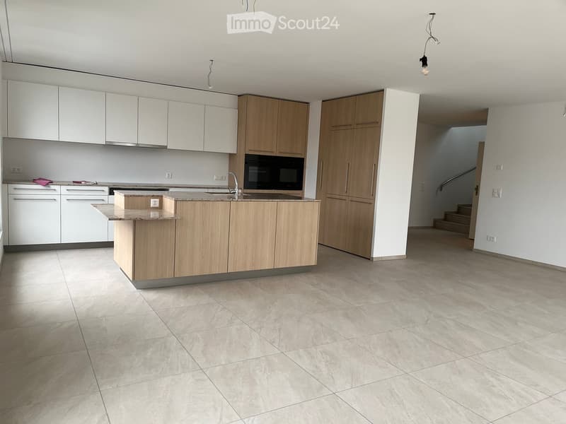 Modern kitchen with white and light wood cabinets, a central island, and a tiled floor.