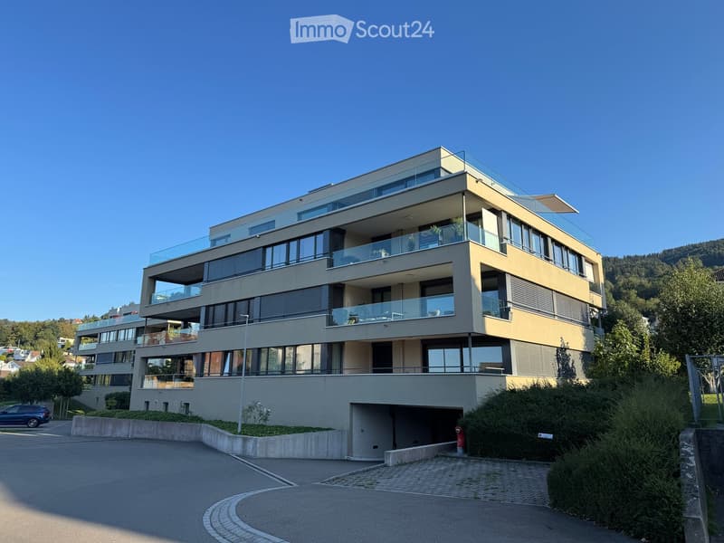 Modern4-story building with large windows, balconies, and a garage entrance.
