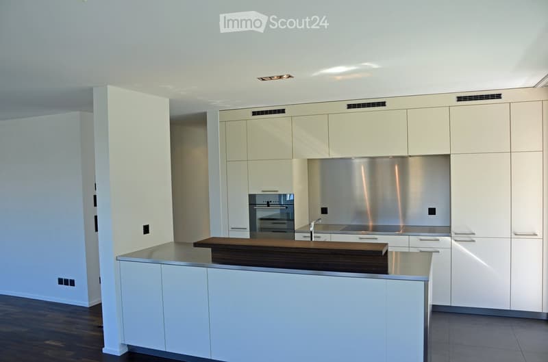 Modern kitchen with white cabinets, stainless steel appliances, and a central island with a wooden countertop.