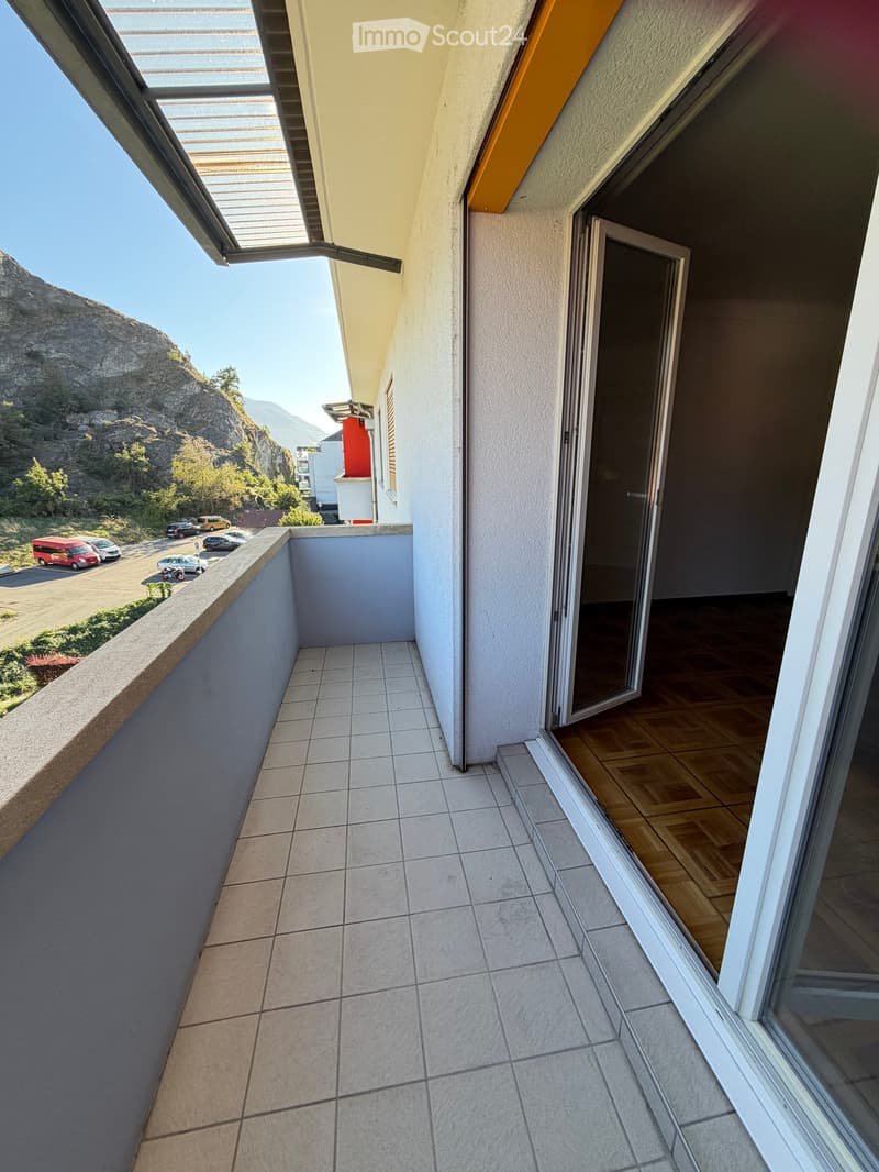 Balcony with tiled floor, open sliding glass door leading to interior, scenic mountain view, and parking area below.