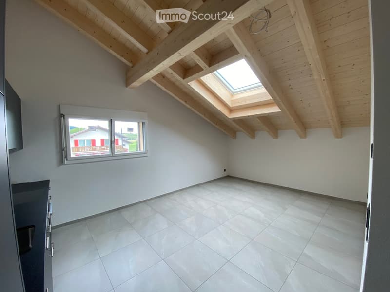 Empty room with white tiled floor, white walls, wooden ceiling beams, and skylight window. No furniture or equipment present.