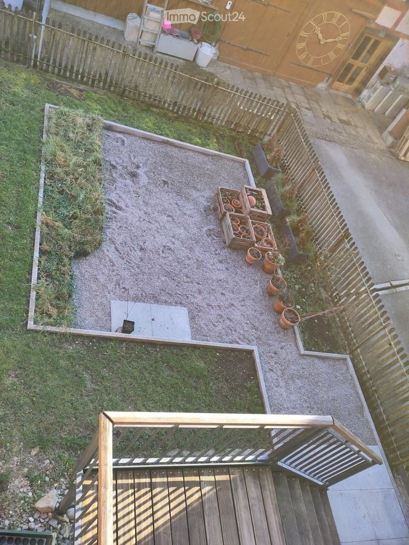 Garden area with wooden deck, gravel, potted plants, and wooden fence.