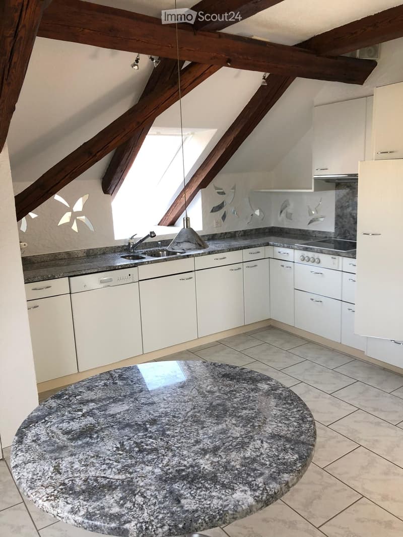 Modern kitchen with white cabinets, granite countertop, sink, dishwasher, stove, and a round granite island table.