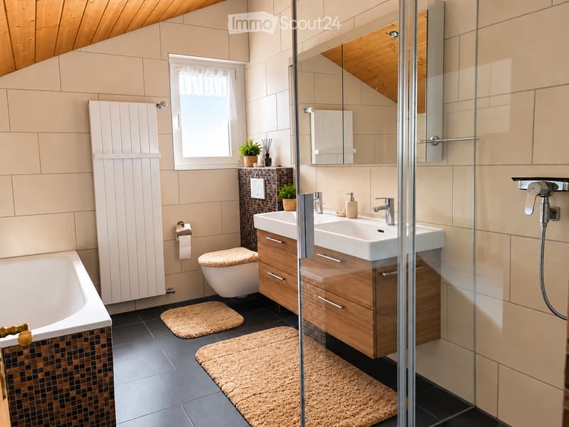 Modern bathroom with a bathtub, toilet, double sink, and a glass-enclosed shower. Features wooden cabinetry, beige tiles, and a skylight window.