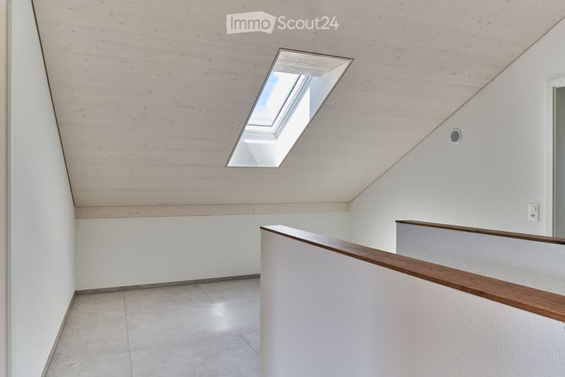 Modern hallway with a skylight, wooden ceiling, white walls, and a wooden railing leading to an upper level.
