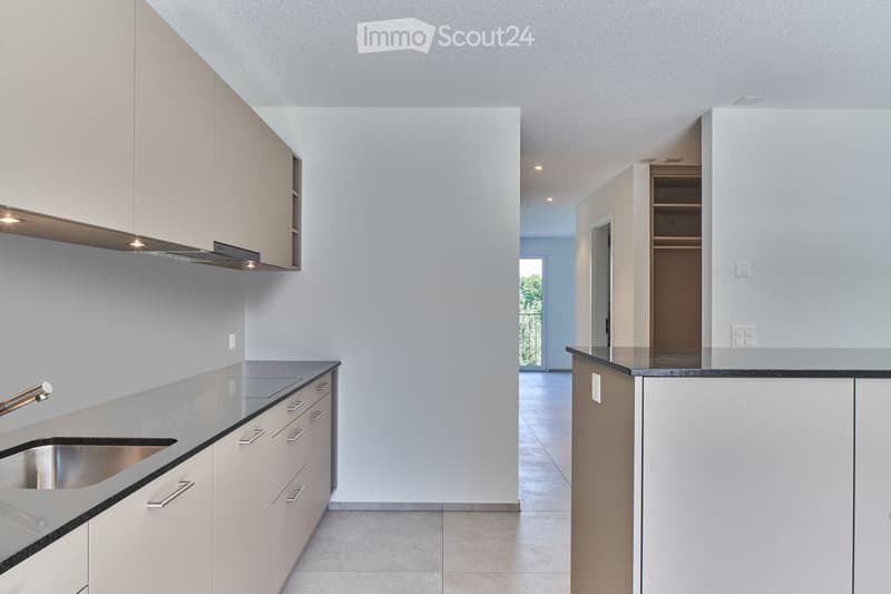 Modern kitchen with white cabinets, stainless steel sink, and sleek countertops.