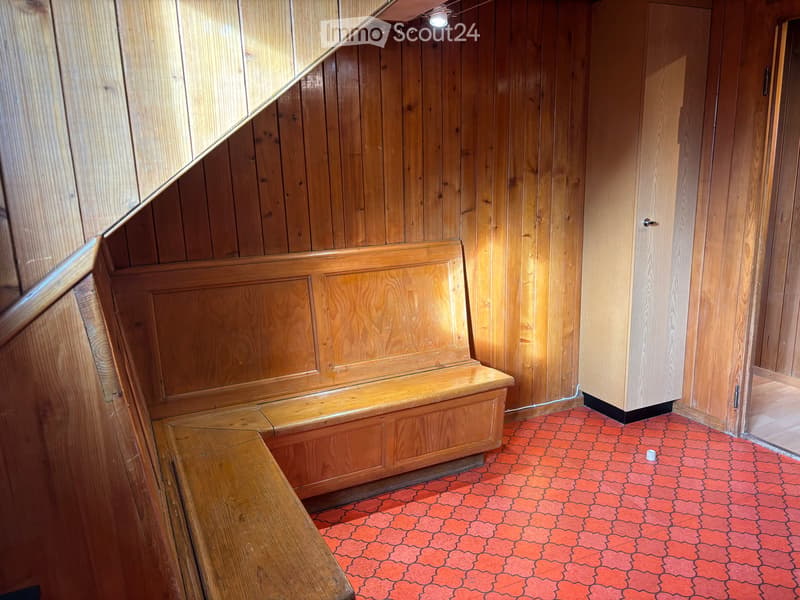 Wooden-paneled hallway with built-in wooden bench seating, red patterned floor, and warm lighting.