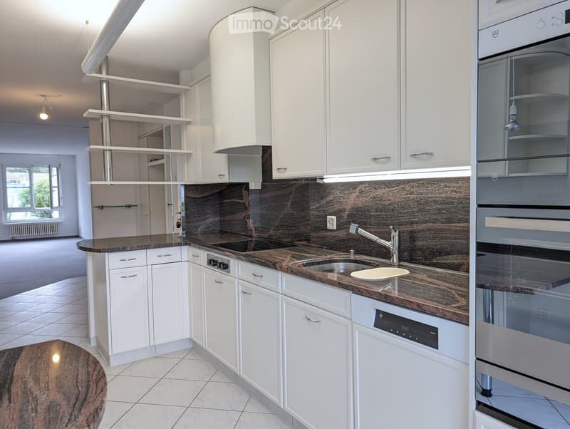 Modern kitchen with white cabinets, dark granite countertops, stainless steel appliances, and a central island.