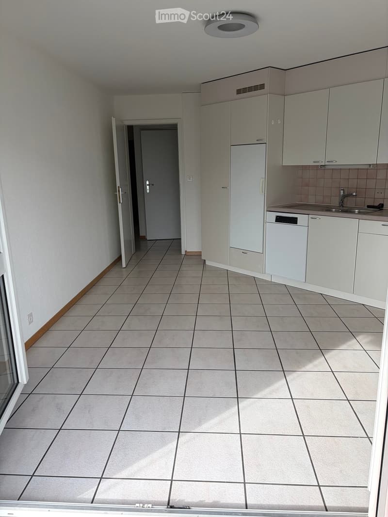 Empty kitchen with tiled floor, white cabinets, and a dishwasher. The space is clean and unfurnished, with no visible appliances or furniture.