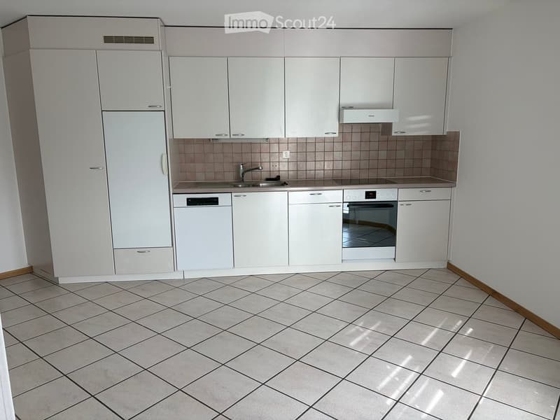 Modern kitchen with white cabinets, tiled backsplash, and built-in appliances including a refrigerator, dishwasher, and oven. The floor is tiled with a diamond pattern.