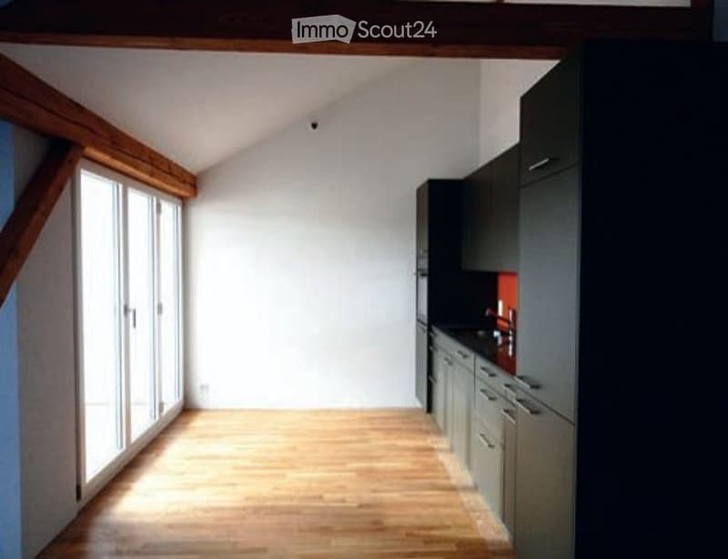 Bright, modern kitchen with wooden flooring, large windows, and dark grey cabinets.