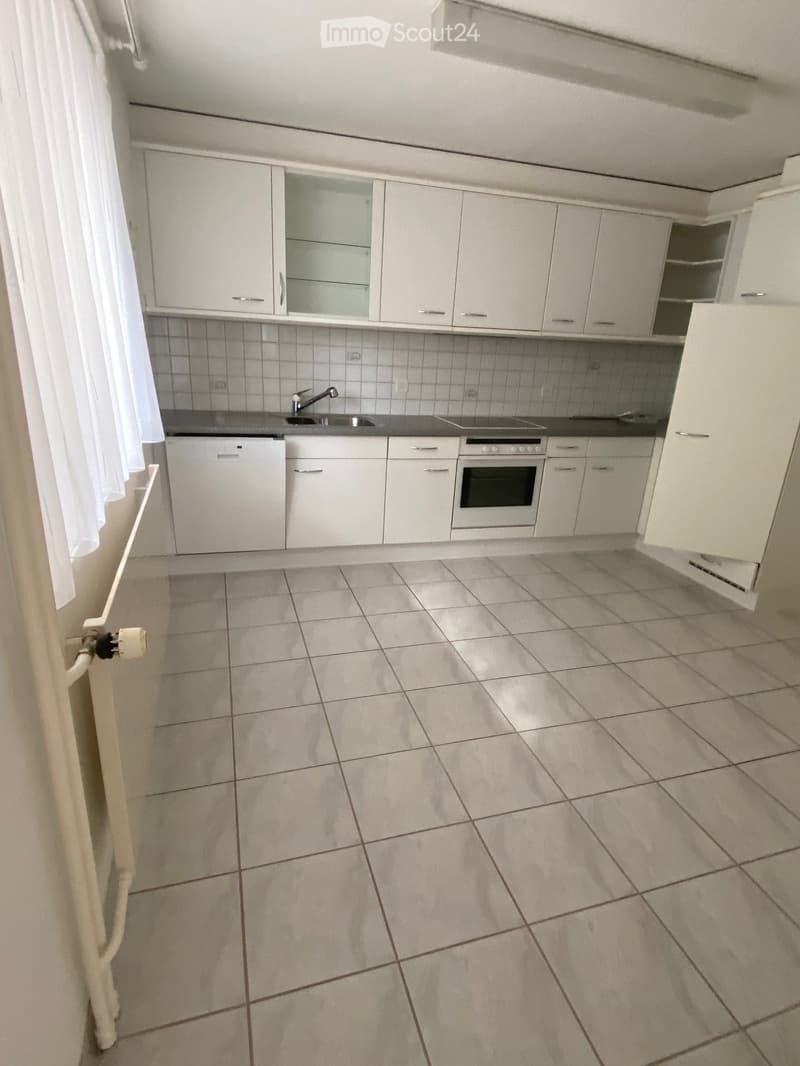Modern kitchen with white cabinets, tiled floor, sink, oven, and dishwasher.