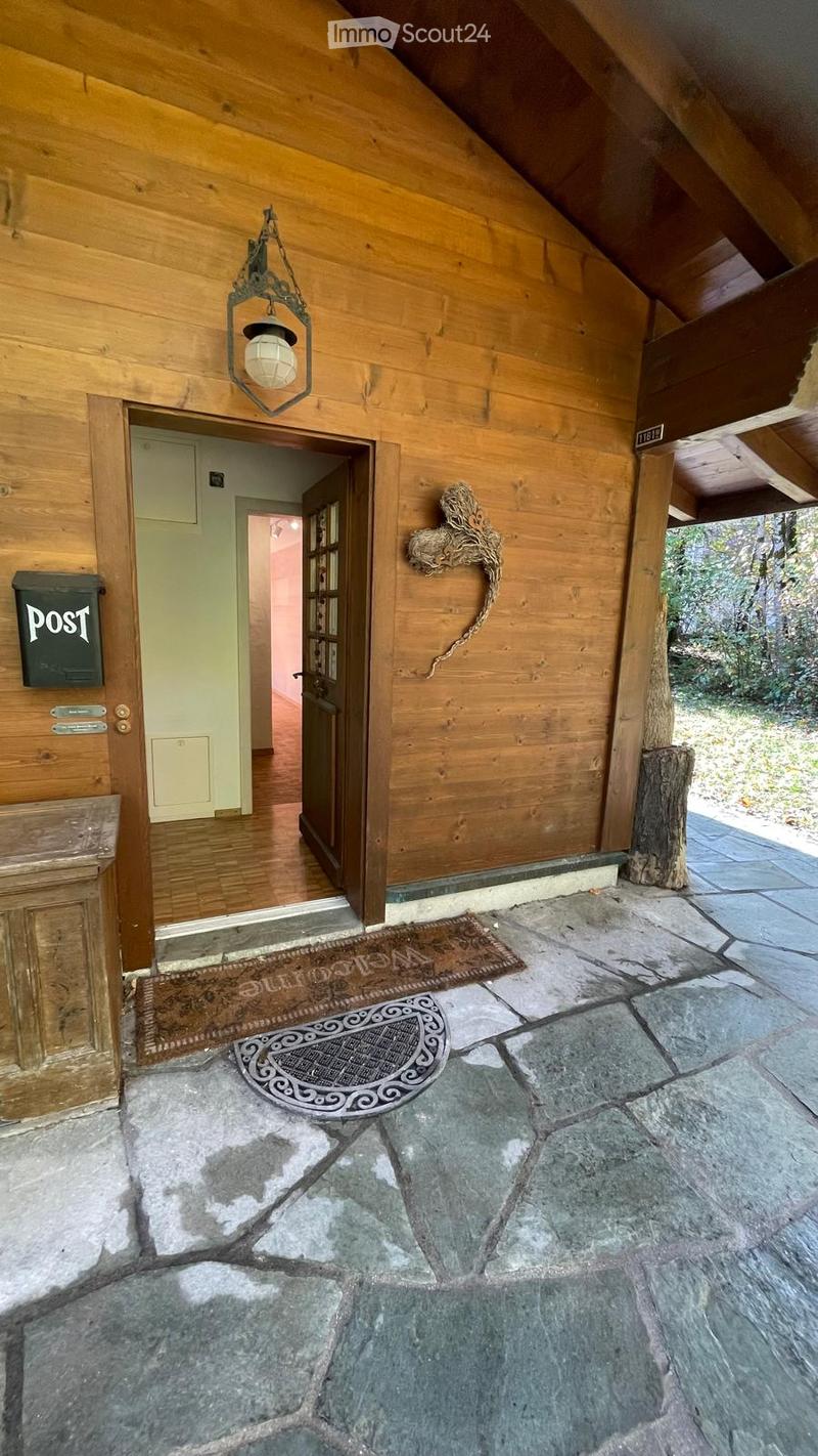 Entrance area with wooden walls, stone flooring, a hanging lantern light fixture, and a decorative doormat.