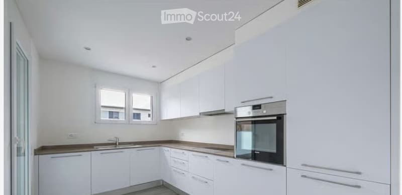 Modern, minimalist kitchen with white cabinets, stainless steel oven, and a sleek countertop.
