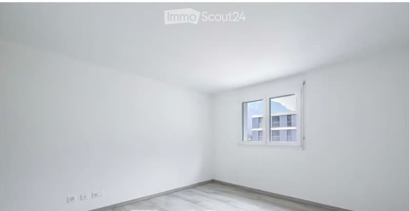 Empty room with white walls, grey tiled floor, and a single window with white frame.