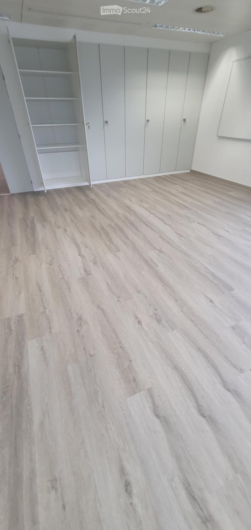 Empty room with light wooden flooring and white walls, featuring built-in closet units with open shelving on one side.