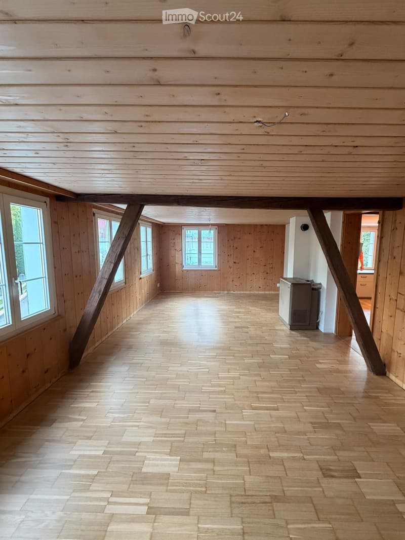 Empty room with wooden walls, wooden floor, and large windows. No furniture or equipment visible.