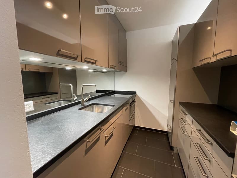 Modern kitchen with sleek, light-colored cabinets, a double sink, and a contemporary faucet. The countertops are dark, and the floor is tiled.