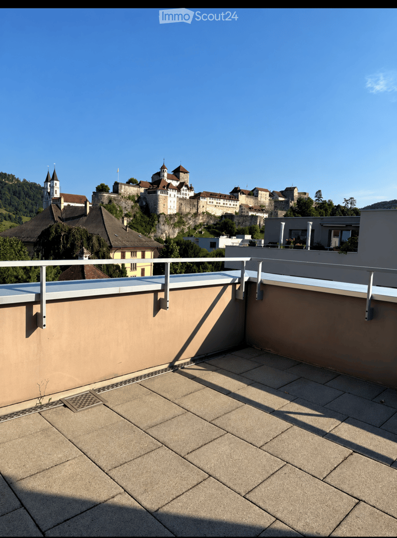 Roof terrace with tiled flooring, metal railing, and a scenic view of a historic town with a castle and church spires.