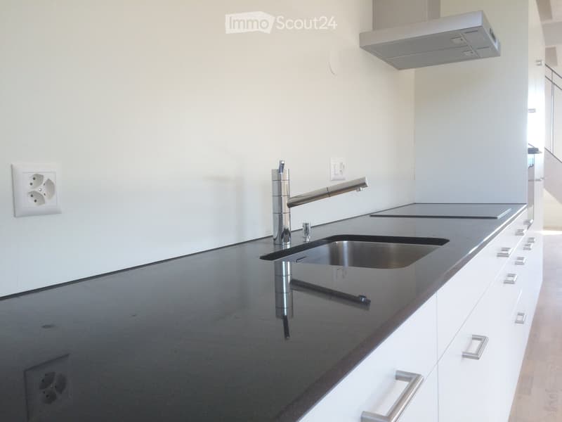 Modern kitchen with sleek black countertops, white cabinets, and a stainless steel faucet.
