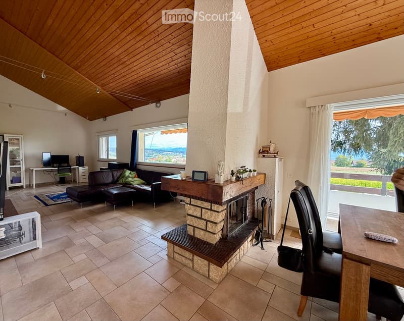 Living room with a fireplace, sofa, coffee table, and large windows offering a scenic view.