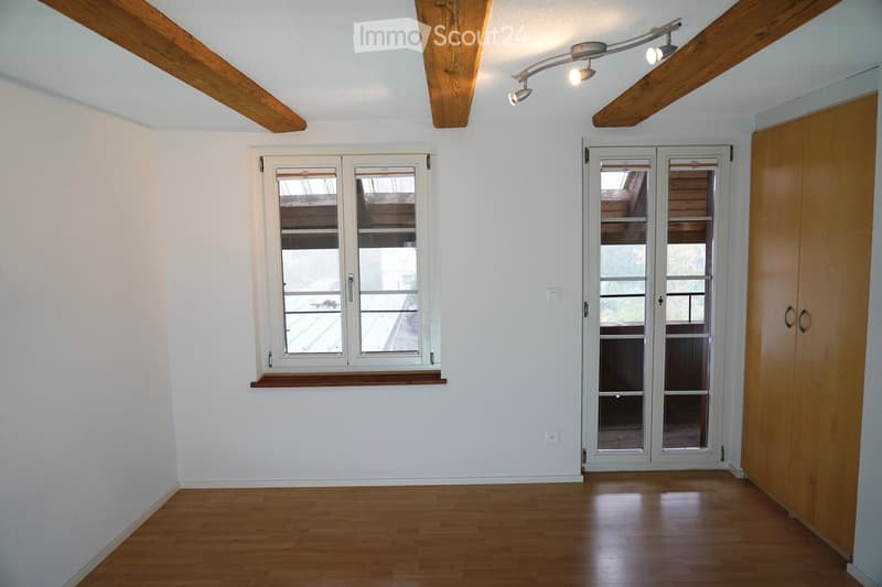 empty room, white walls, wooden floors, wooden ceiling beams, windows, doors