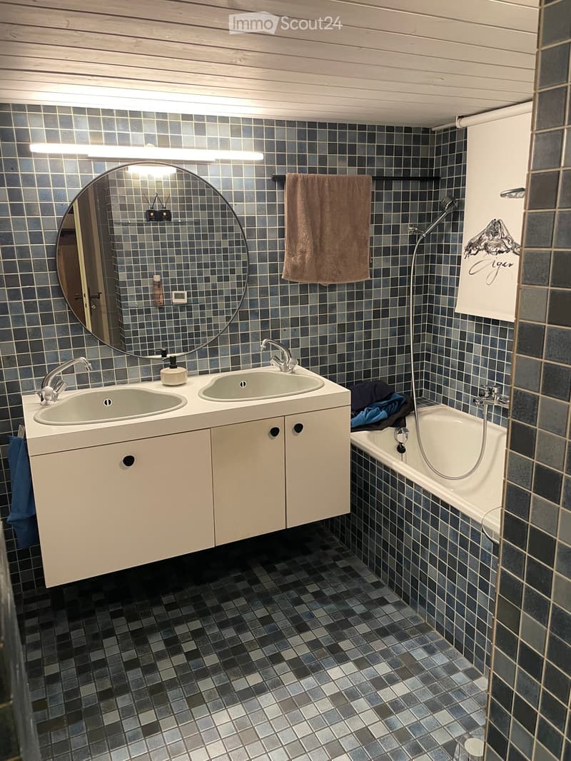 Bathroom with double sink, mirror, bathtub, and tiled walls and floor.