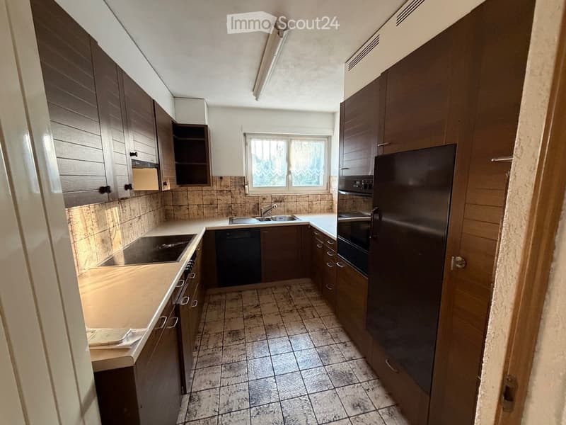 Modern kitchen with dark wooden cabinets, stainless steel appliances, tiled floor, and a window above the sink.