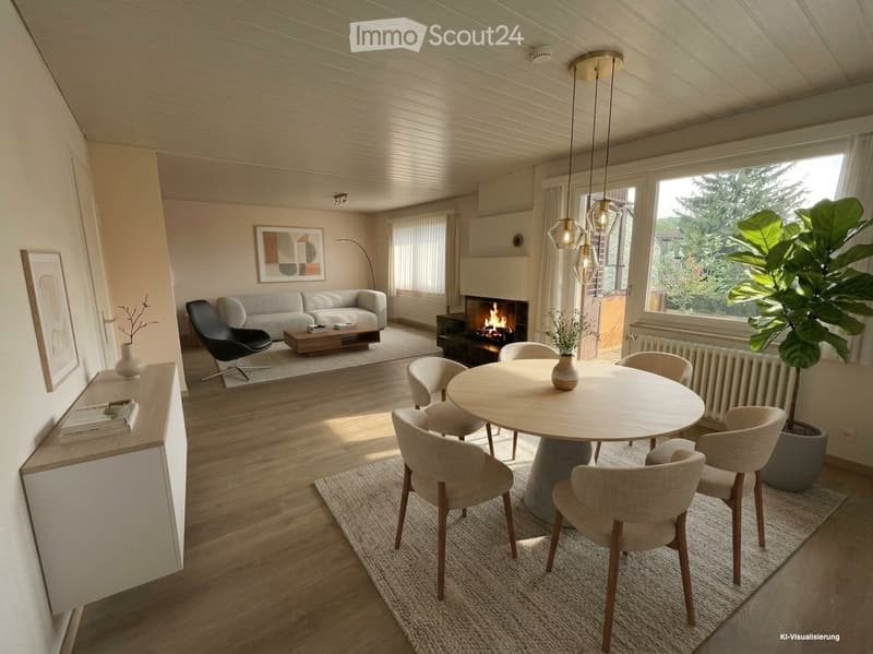 Modern living and dining area with a fireplace, sofa, coffee table, dining table with chairs, and large windows with a view of greenery.