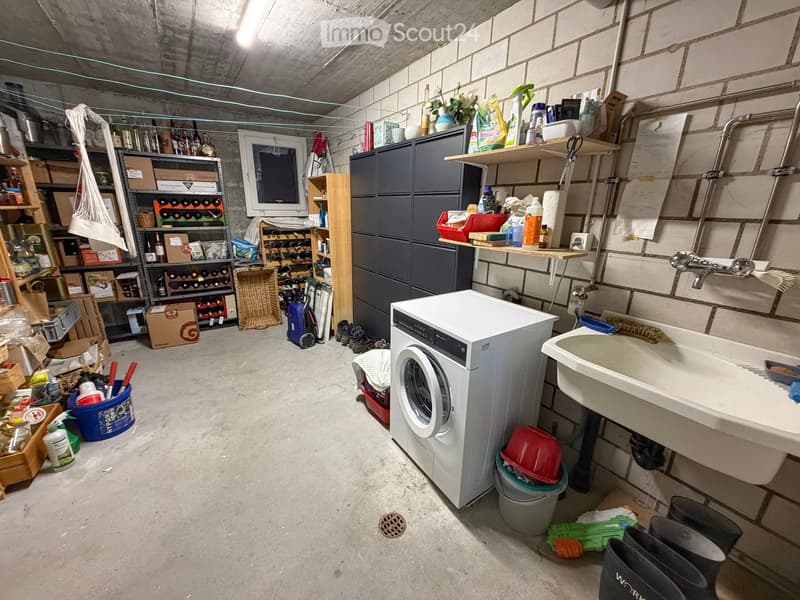 Utility room with a washing machine, sink, shelves, wine rack, and various storage items.