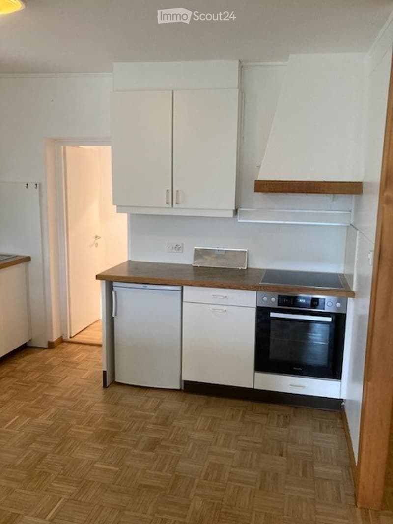 Modern kitchen with white cabinets, wooden countertops, and stainless steel appliances including a refrigerator, dishwasher, and oven.