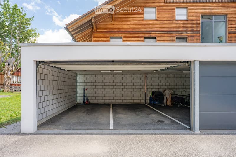 Two-story building with a raised ground floor garage, wooden upper level, and tiled interior walls.
