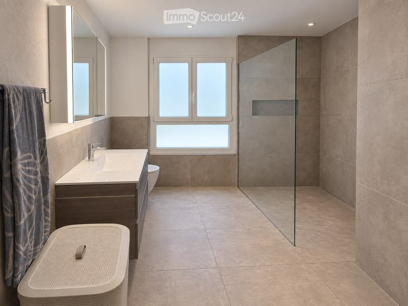 Modern bathroom with a large window, a sink with a modern faucet, a mirrored cabinet, a bathtub, and a glass-enclosed shower area.