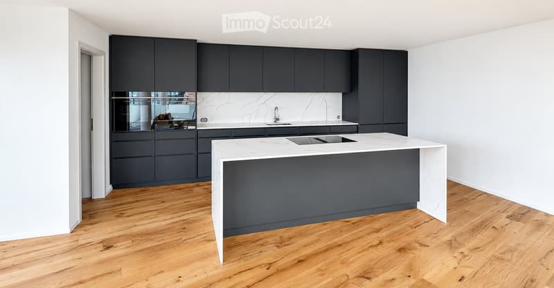 Modern kitchen with dark grey cabinets, white marble island, and wooden flooring.