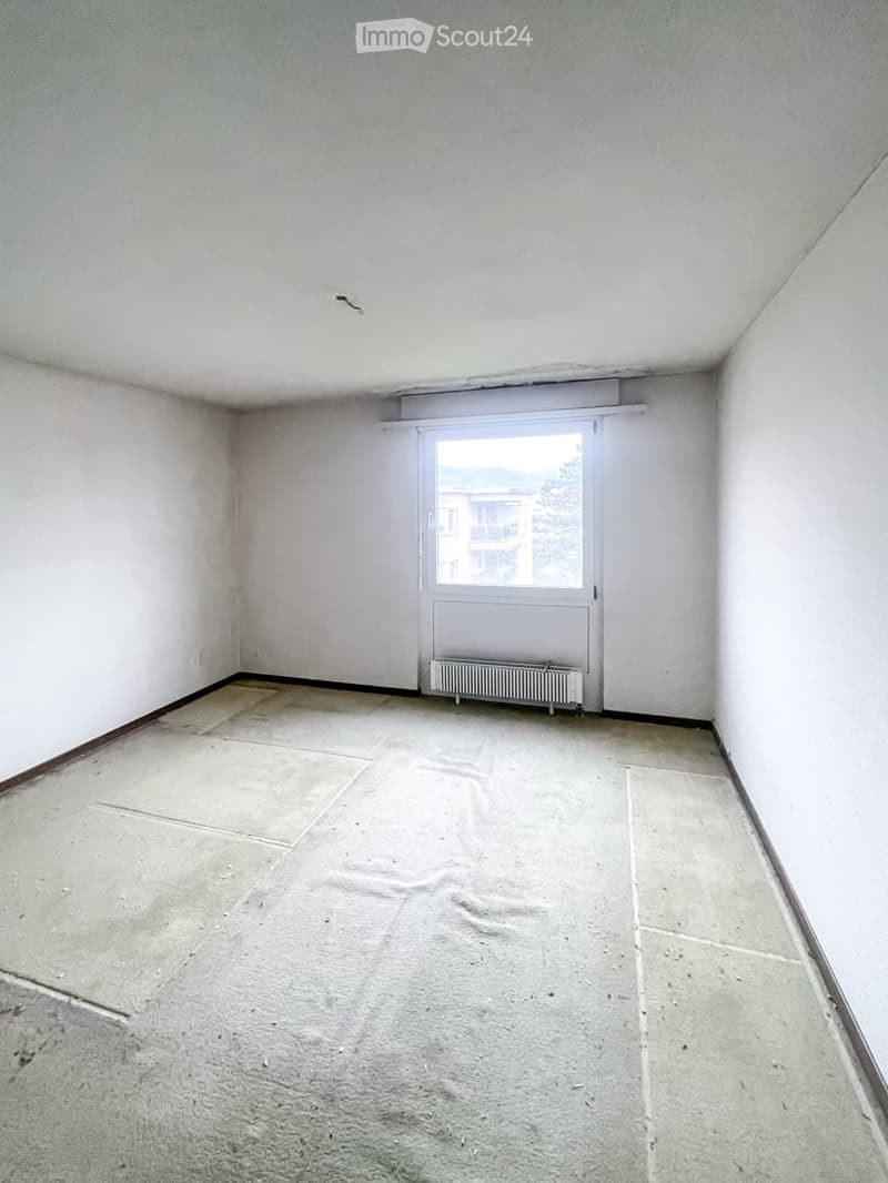 Empty room with white walls, tiled floor, and a single window with a radiator below it.