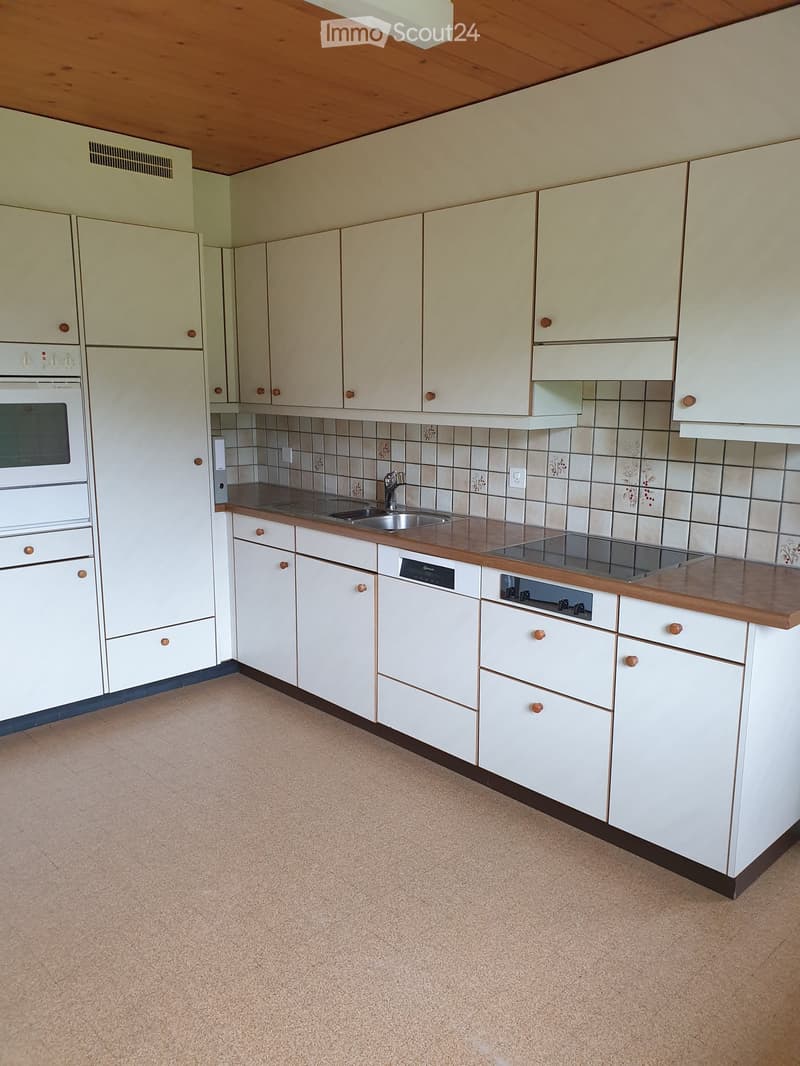 Modern kitchen with white cabinets, wooden countertops, stainless steel sink, and built-in appliances including an oven and stove.