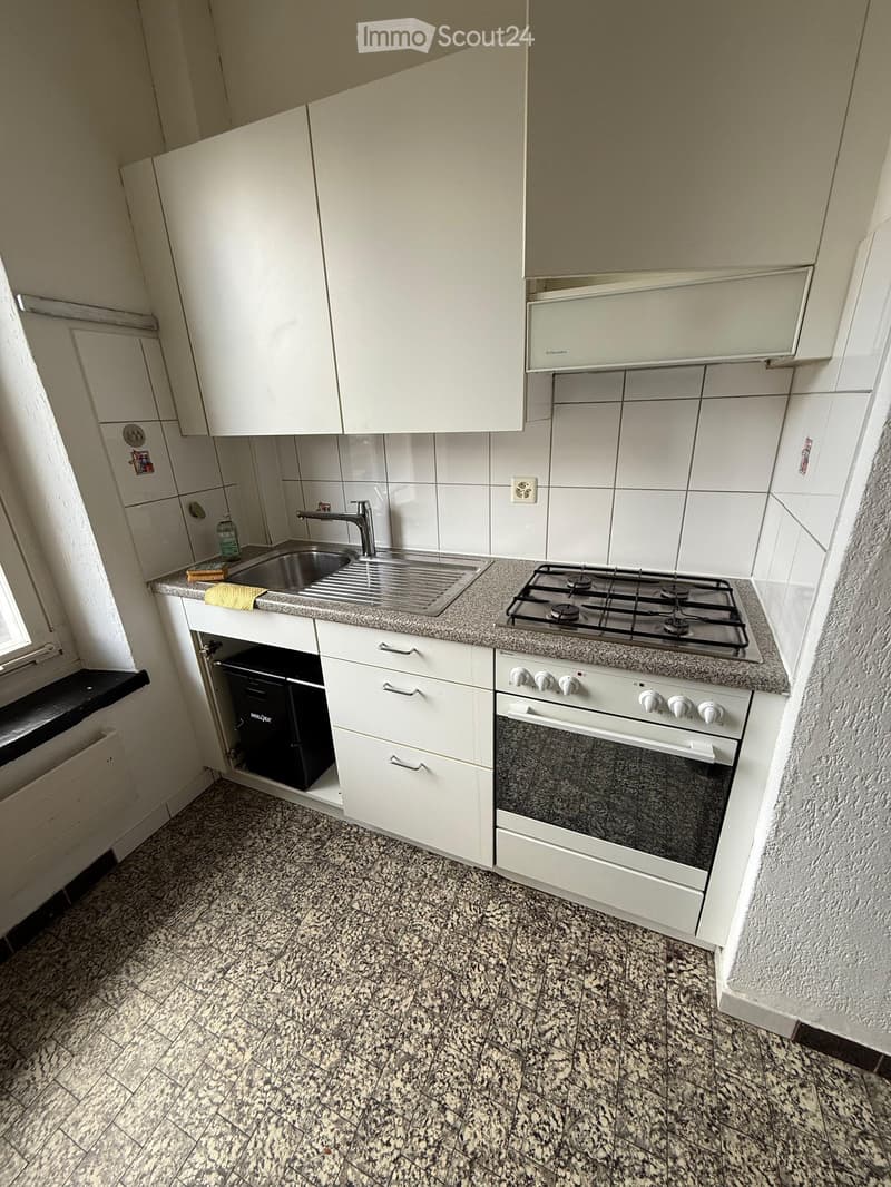 Compact kitchen with white cabinets, granite countertop, gas stove, oven, and sink.