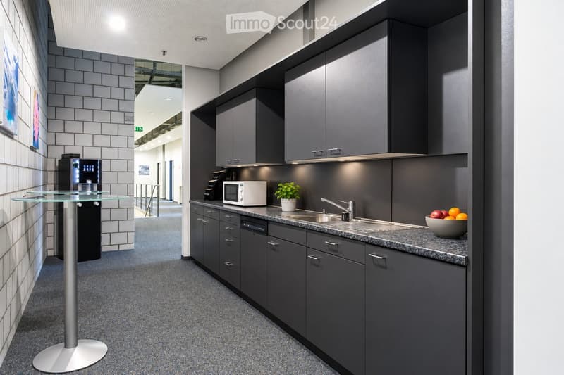 Modern kitchen with dark grey cabinets, granite countertop, microwave, sink, and a small table with a glass top.