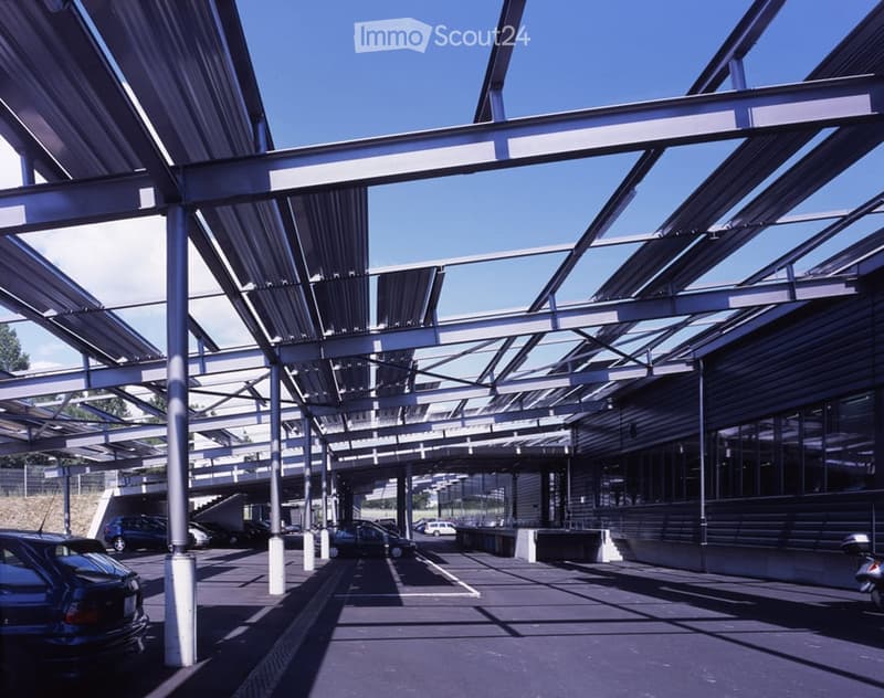 Modern covered parking area with metal framework and several parked cars.