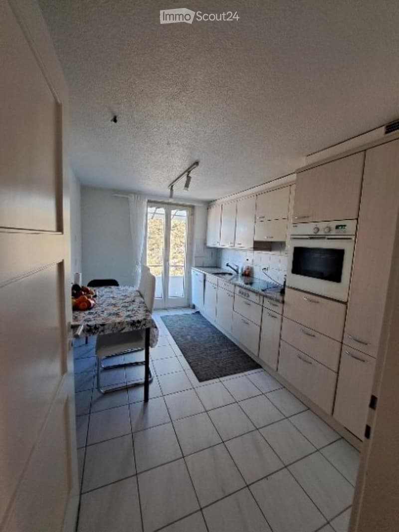 Modern kitchen with white cabinets, tiled floor, and a small dining area with a table and chairs.