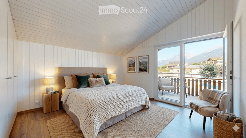 Cozy bedroom with a large bed, nightstand, lamp, and a view of the mountains through an open sliding door leading to a balcony.