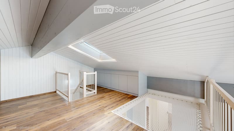 Bright, open loft-style space with wooden flooring, white paneled walls, and a skylight. Features a staircase leading to an upper level, with modern railings and built-in cabinetry.