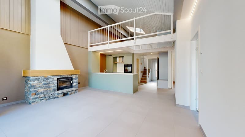 Modern open-plan living space with a stone fireplace, kitchen island, and a staircase leading to an upper level.
