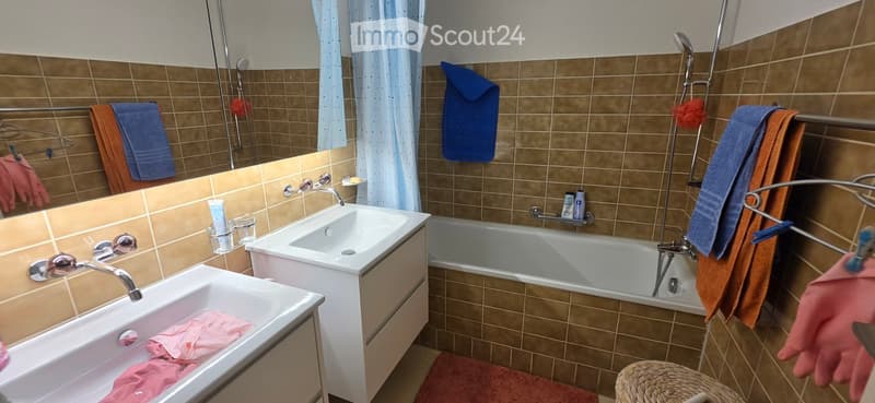 Bathroom with two sinks, a bathtub, and various towels and toiletries.