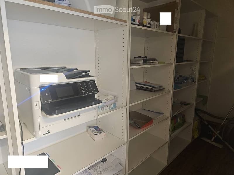 A small, organized room with white shelving units holding a printer, books, and various office supplies.