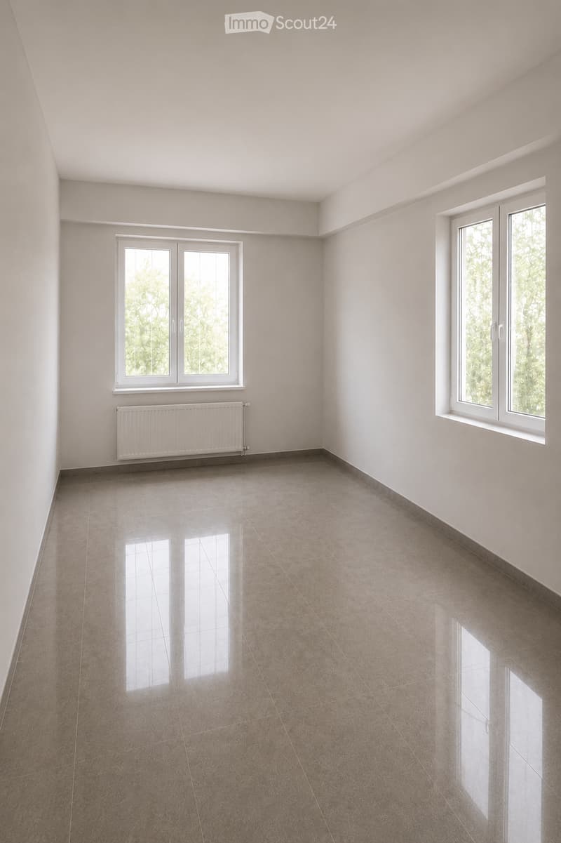 Empty room with light-colored walls, tiled floor, and two windows with white frames. A radiator is visible below one window.