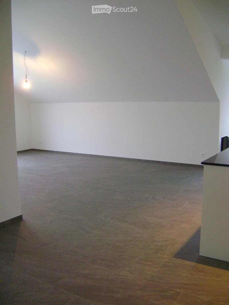Empty room with light-colored walls and a tiled floor, featuring a single light fixture on the wall.