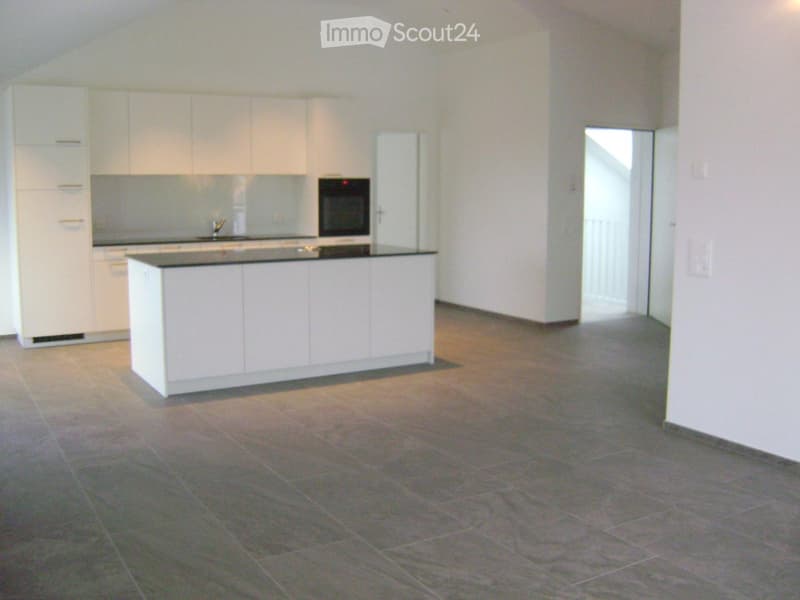 Empty kitchen with white cabinets, a countertop, and a sink, featuring a tiled floor and an open doorway leading to another room.