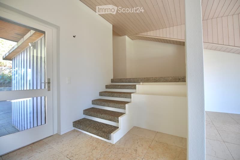 Modern hallway with white walls, tiled floor, and a staircase leading upwards with granite steps and white risers.
