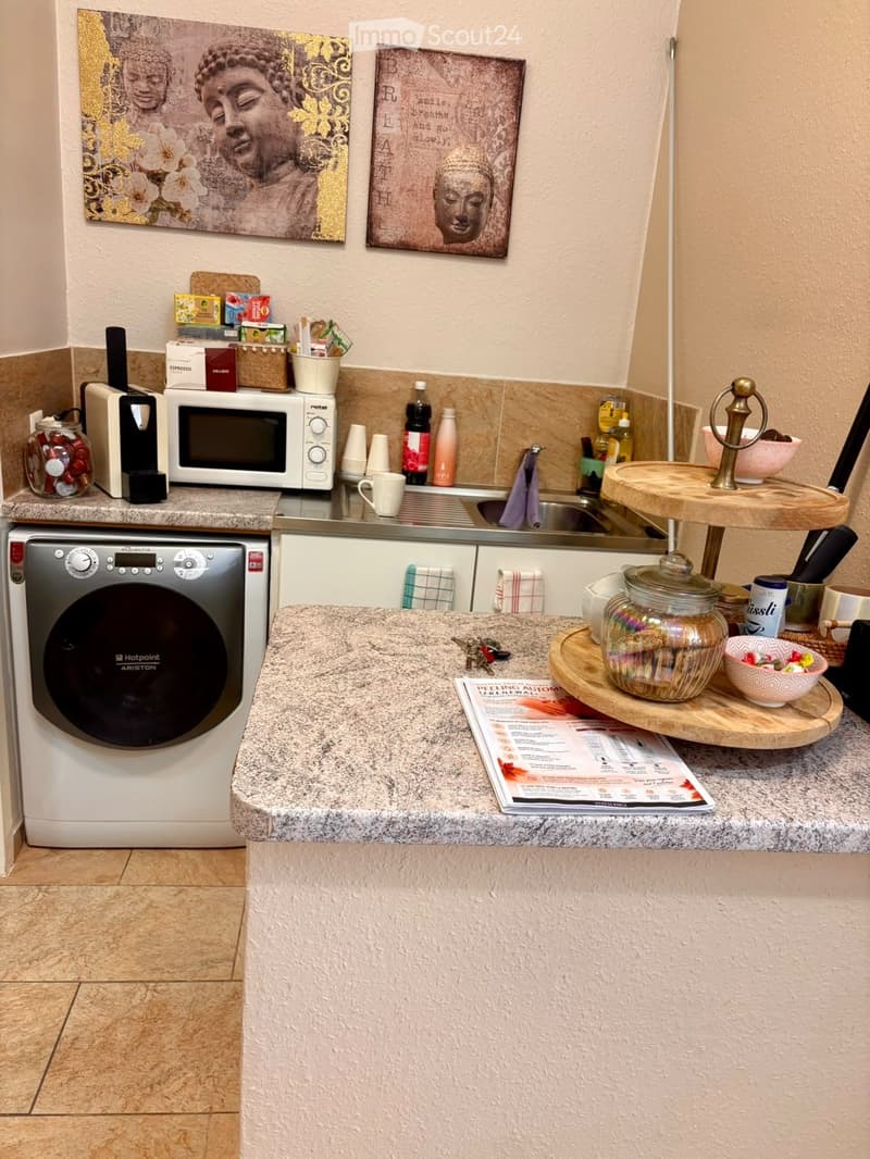 Modern kitchen with granite countertops, microwave, dishwasher, coffee maker, and various kitchen items on the counter.